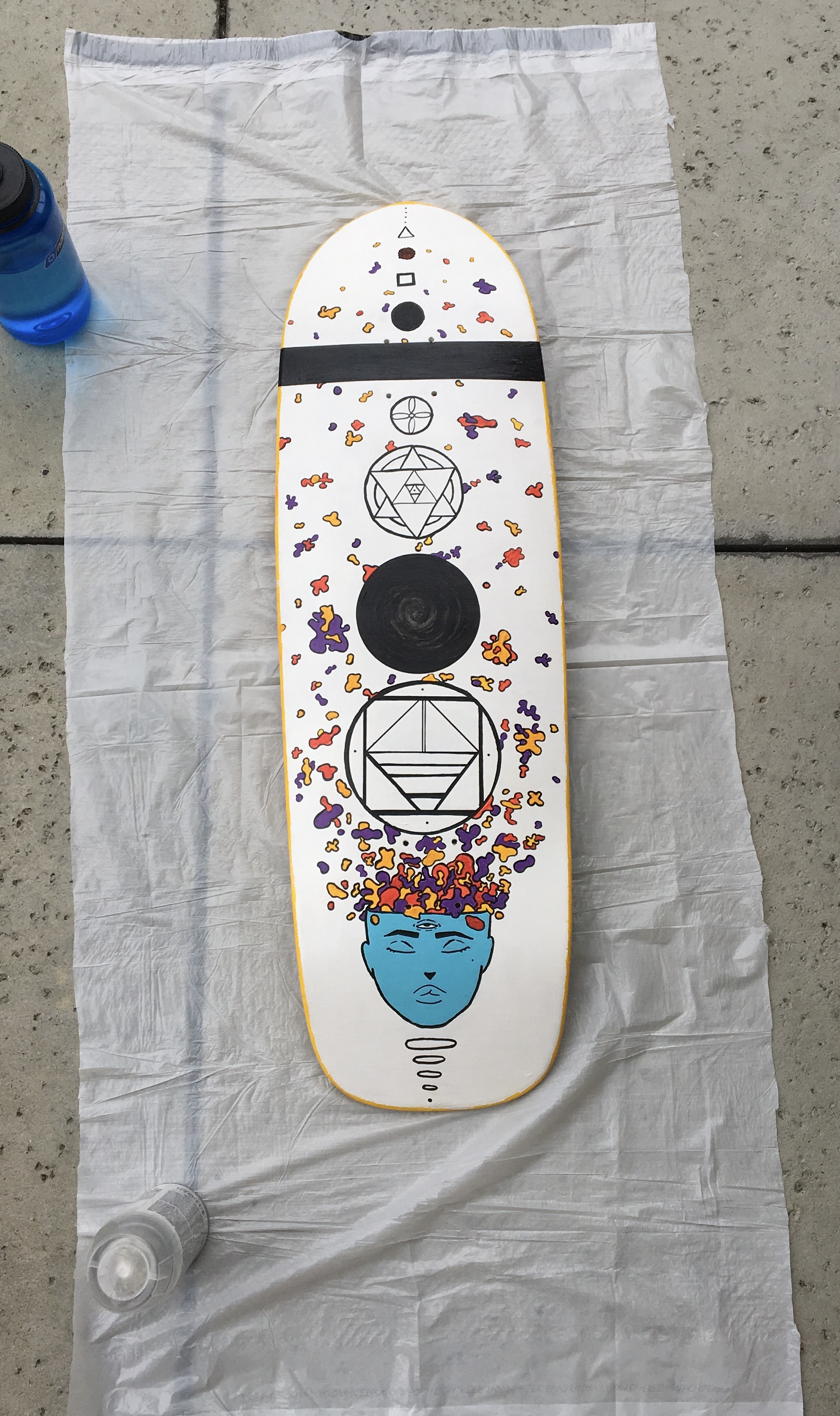 board fully painted outside drying with blue face red yellow purple organic shapes and black geometric shapes